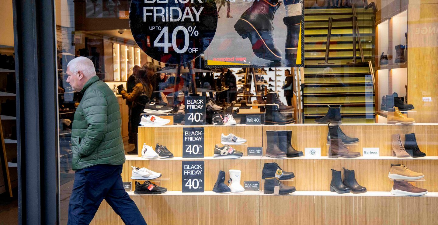 En mann passerer et butikkvindu med Black Friday-reklame.