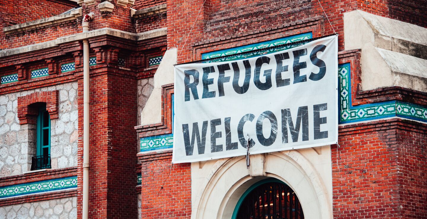 "Refugees Welcome" banner hanging on brick building