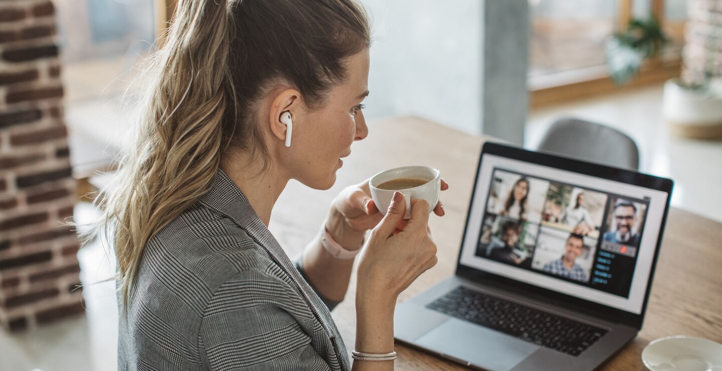De fleste medarbeidere kommer ikke til å jobbe fra hjemmekontor hele tiden eller samtidig. Stadig flere møter vil bli hybride ved at noen deltar fysisk og andre digitalt, skriver  Linda Lai. (Fotoillustrasjon av en dame på café i møte med andre digitalt. Fotograf: Svetlana Damijanac)