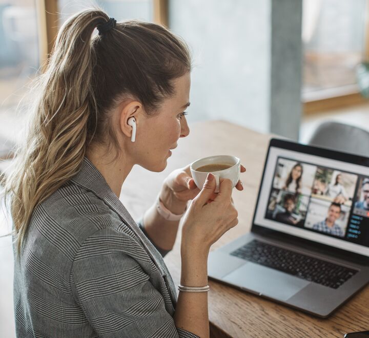 De fleste medarbeidere kommer ikke til å jobbe fra hjemmekontor hele tiden eller samtidig. Stadig flere møter vil bli hybride ved at noen deltar fysisk og andre digitalt, skriver  Linda Lai. (Fotoillustrasjon av en dame på café i møte med andre digitalt. Fotograf: Svetlana Damijanac)