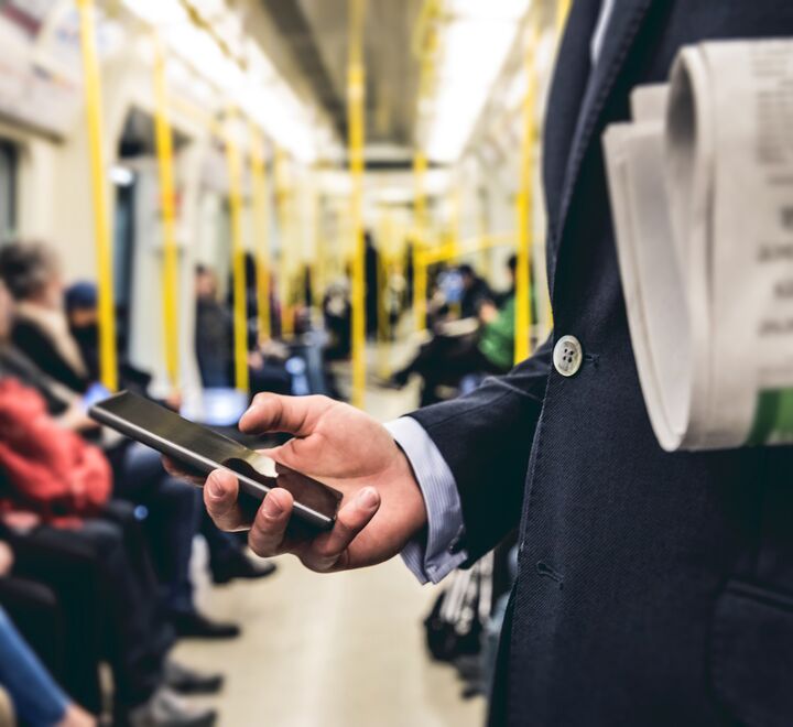 Mann som leser på mobilen på t-banen.