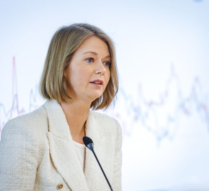 Sentralbanksjef Ida Wolden Bach foran en skjerm med grafer