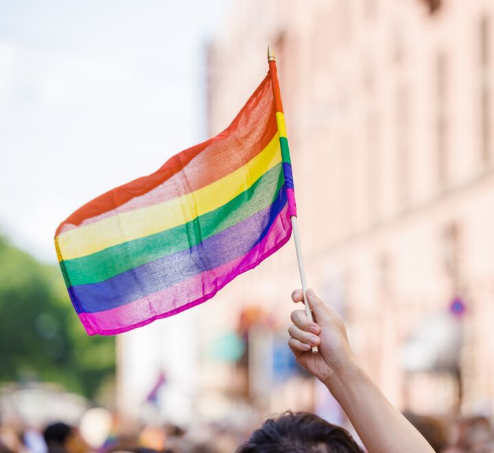 Pride-paraden 2023. Nærbilde av en hånd som holder et Pride-flagg.