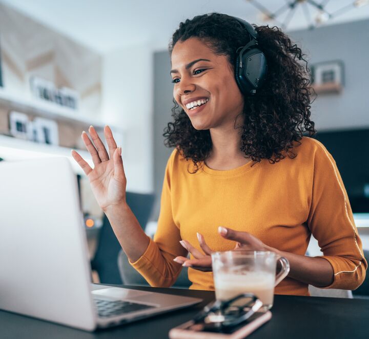 En dame som jobber på en laptop med kaffe i hånda