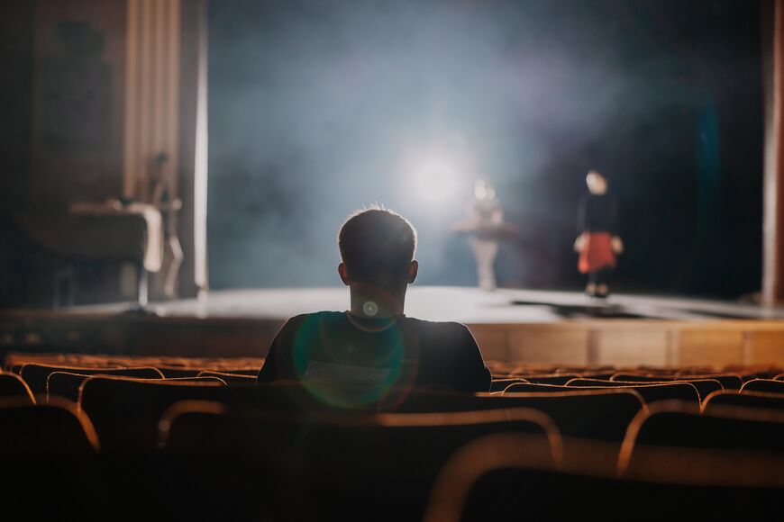 Man sitting in a theatre looking at bright stage