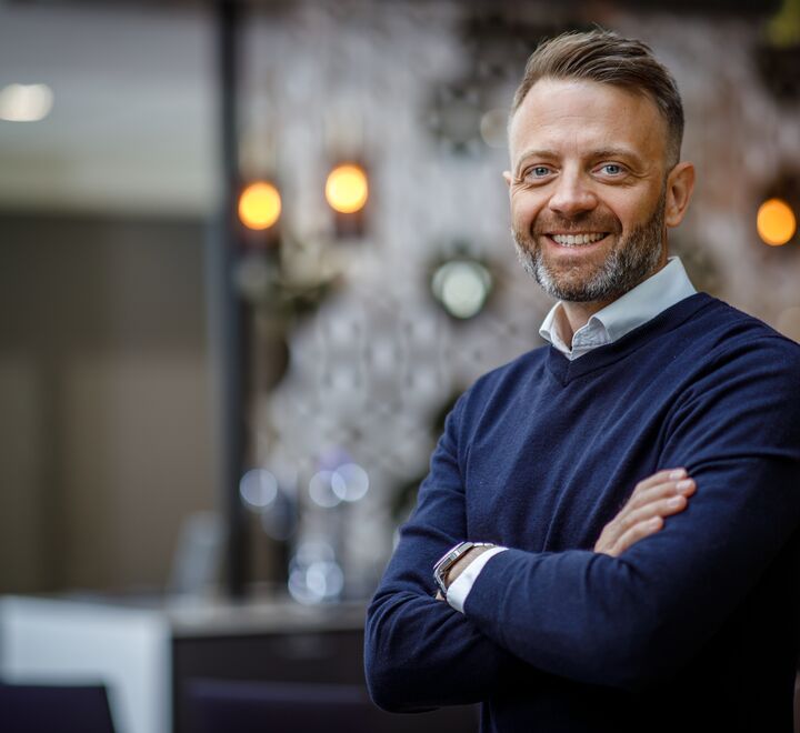 Smilende mann med hendene i kryss