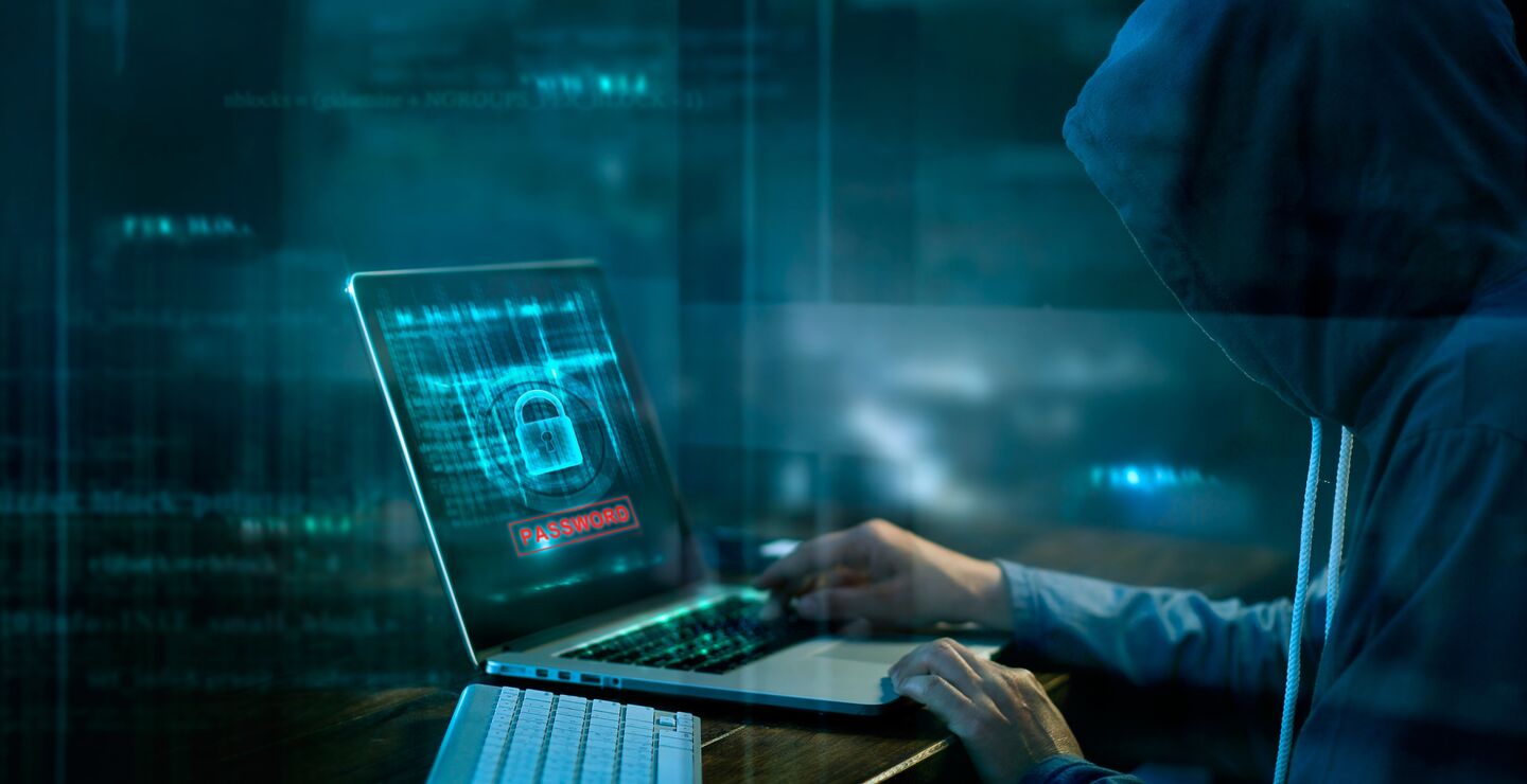 Person med hettegenser over hodet foran en laptop