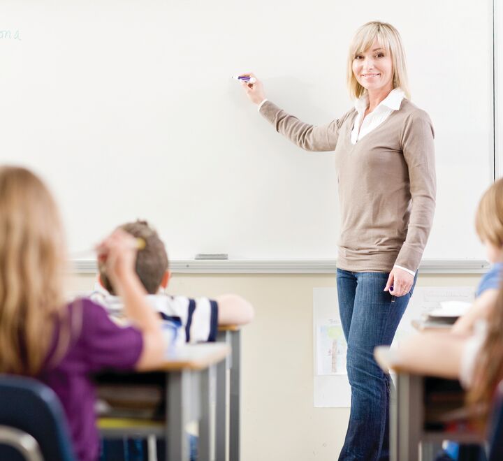 Bilde av en lærer foran skolebarn.