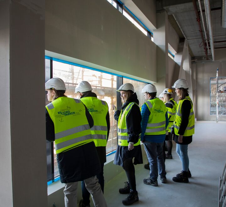 Mennesker med gule vester og hjelm i et byggeprosjekt