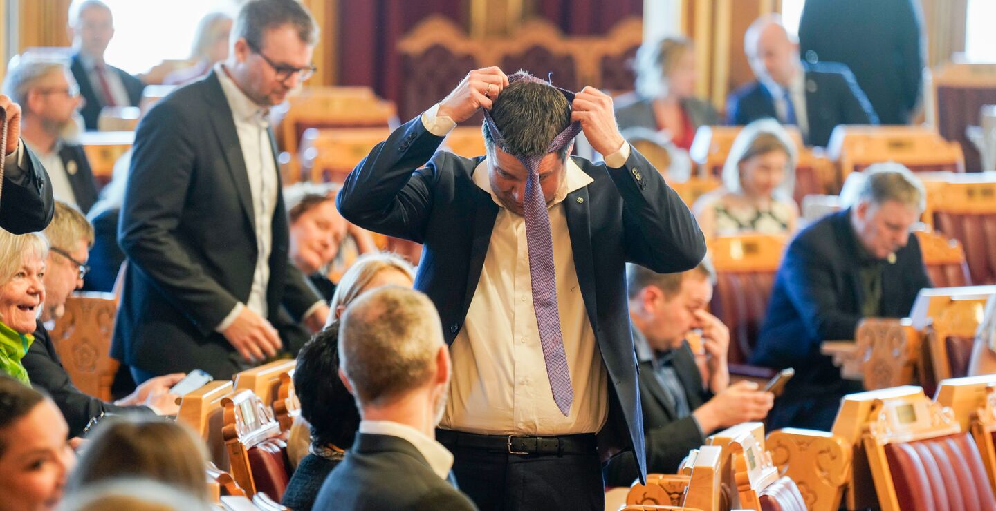 Geir Pollestad tar på seg slipset før debatten om inntektsberegningen for landbruket i Stortingssalen i 2024