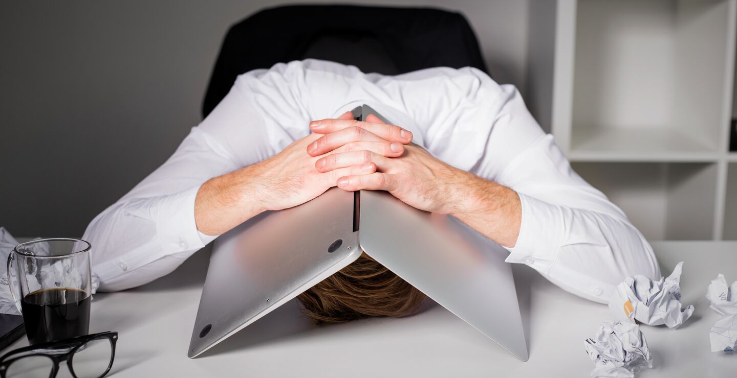 Stresset og fortvilet mann med laptopen over hodet