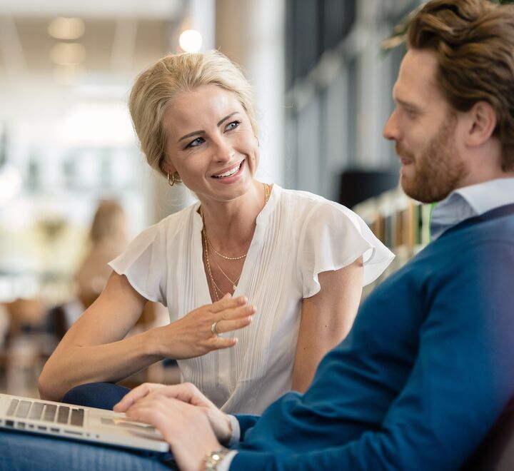 A woman explaining something to a man working on his laptop