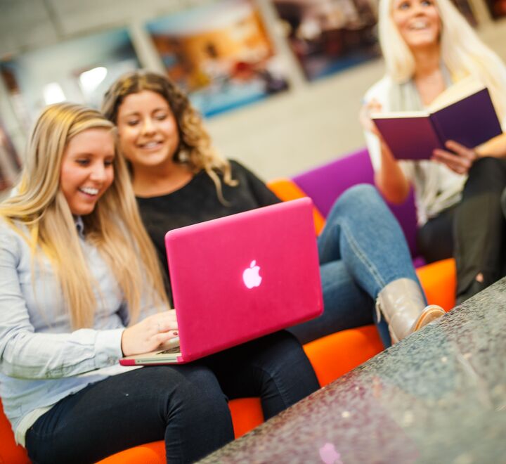 Studenter som sitter å skriver på en rosa pc