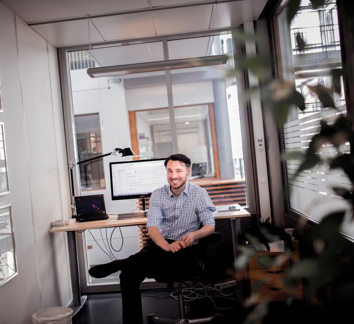 A man smiling at his desk