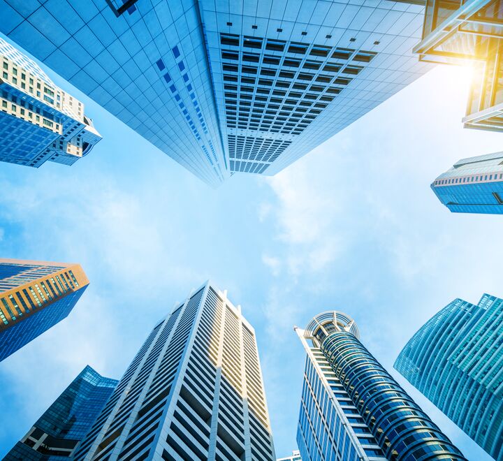 Skyskrapere sett nedenfra og opp med blå himmel.