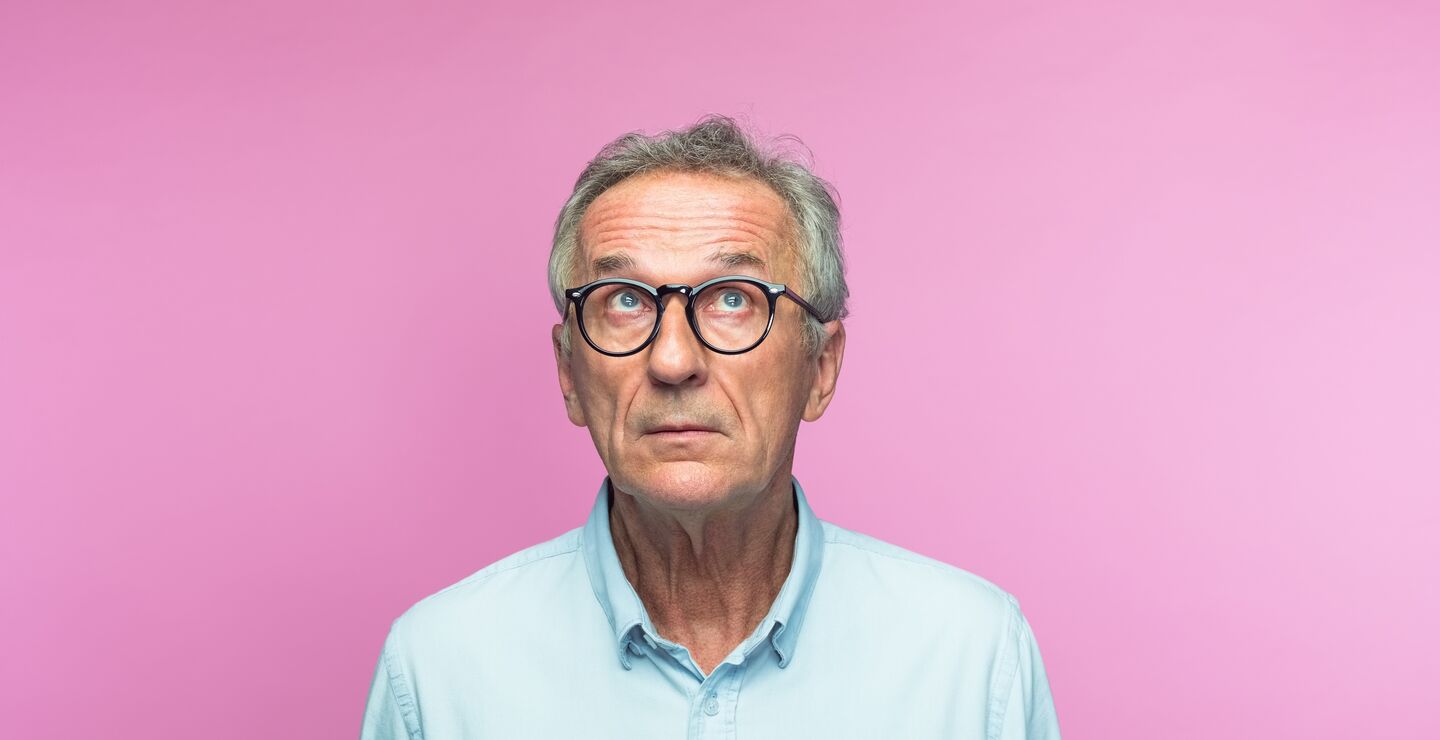 Usikker og tankefull mann foran rosa bakgrunn.