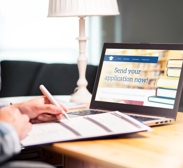 Young person writing college application form with pen and paper