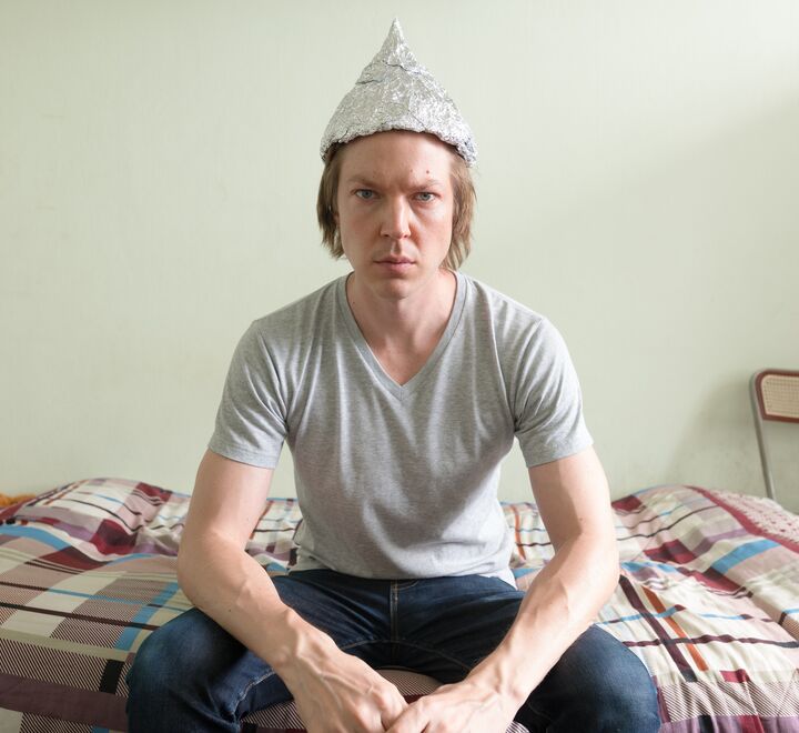 Young man on bed wearing tin foil hat