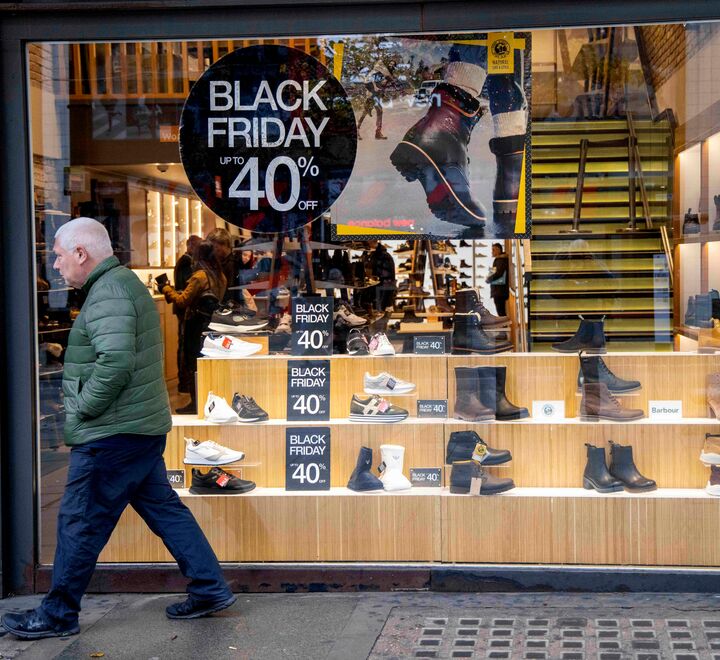 En mann passerer et butikkvindu med Black Friday-reklame.