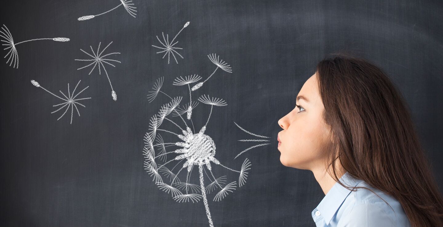 Woman blowing seeds of a dandelion