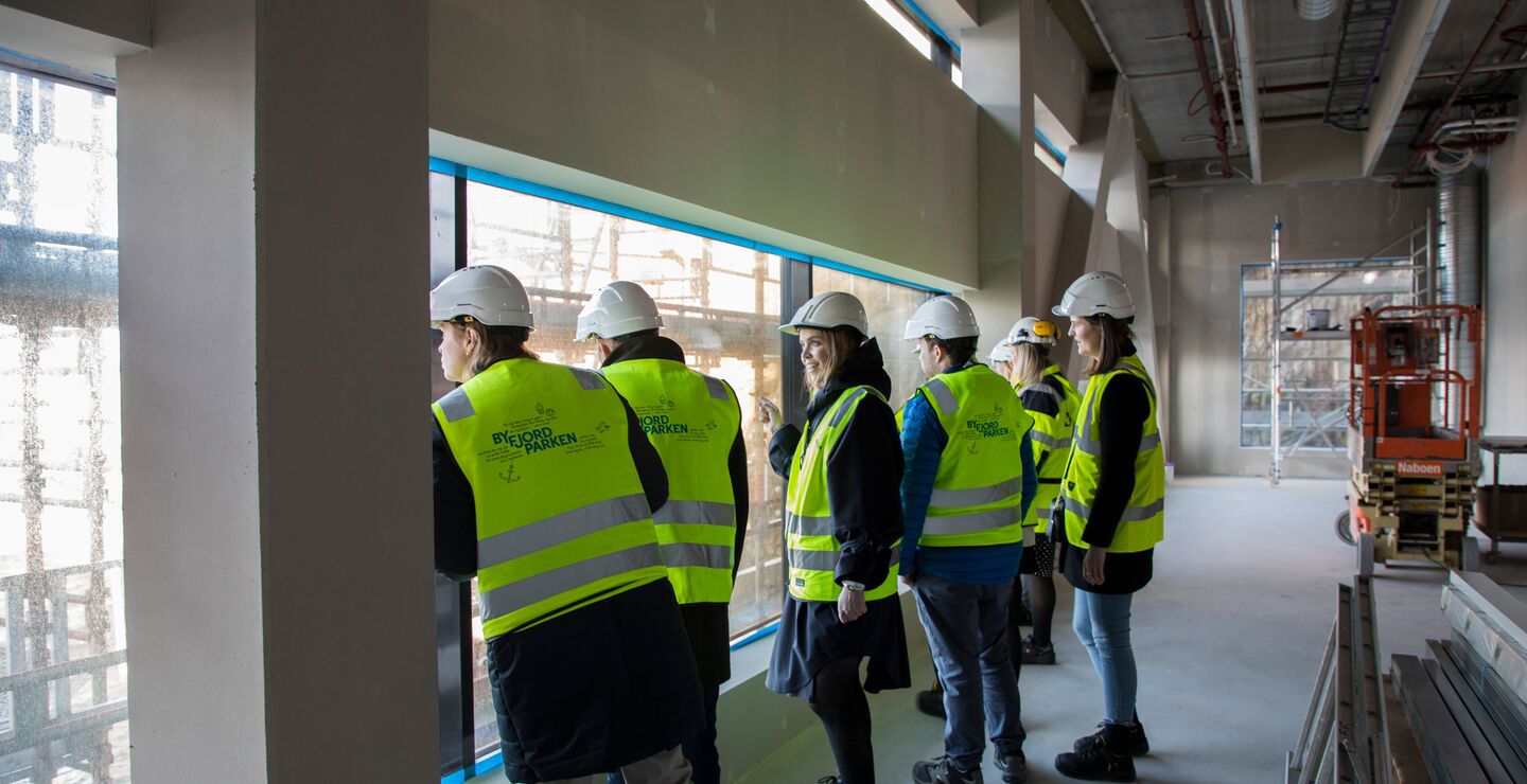 Mennesker med gule vester og hjelm i et byggeprosjekt