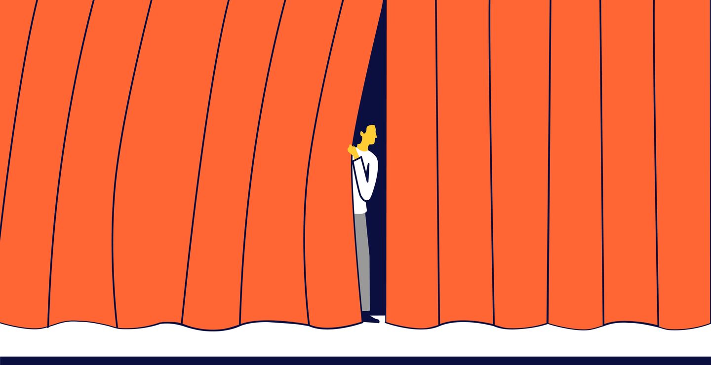 En nervøs mann som kikker ut fra et sceneteppe