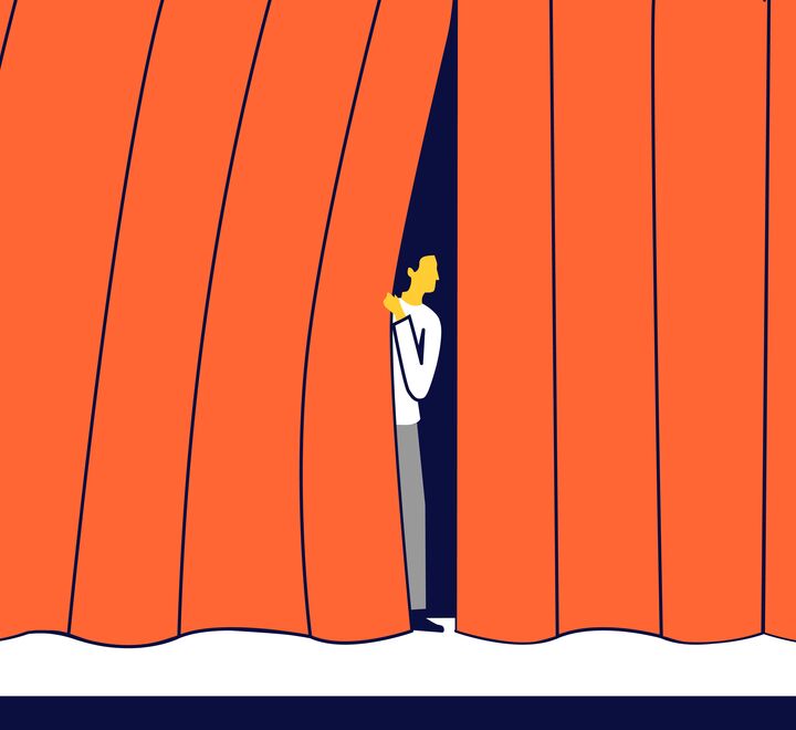 En nervøs mann som kikker ut fra et sceneteppe