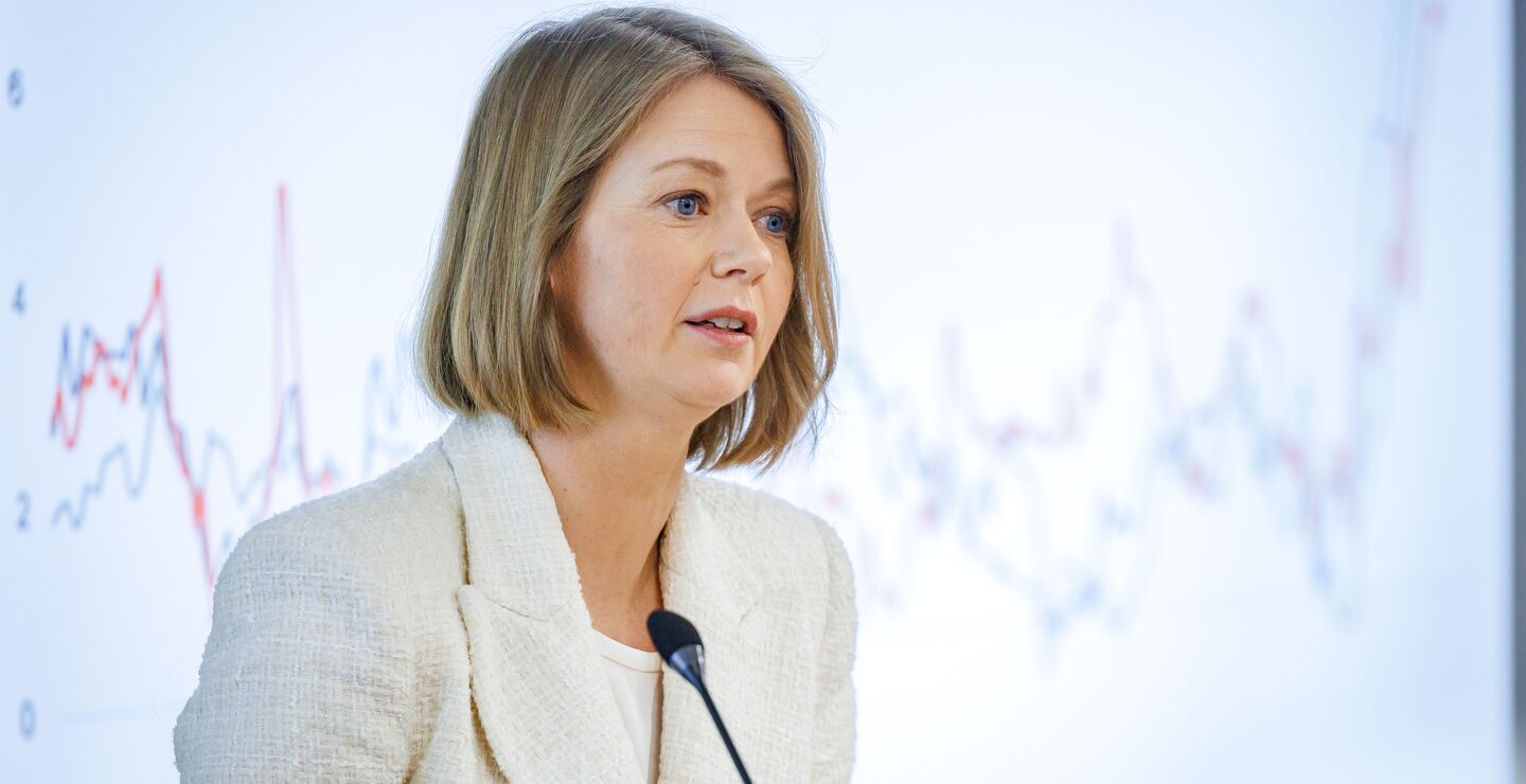 Sentralbanksjef Ida Wolden Bach foran en skjerm med grafer