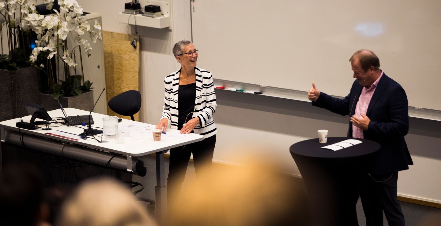 Peggy Brønn by the podium under her lecture of how understanding the power of communication makes great leaders