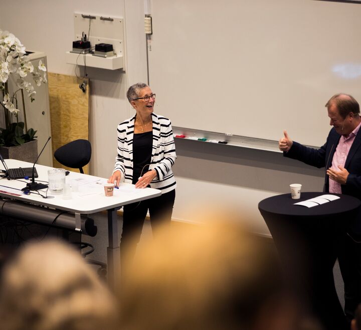Peggy Brønn by the podium under her lecture of how understanding the power of communication makes great leaders