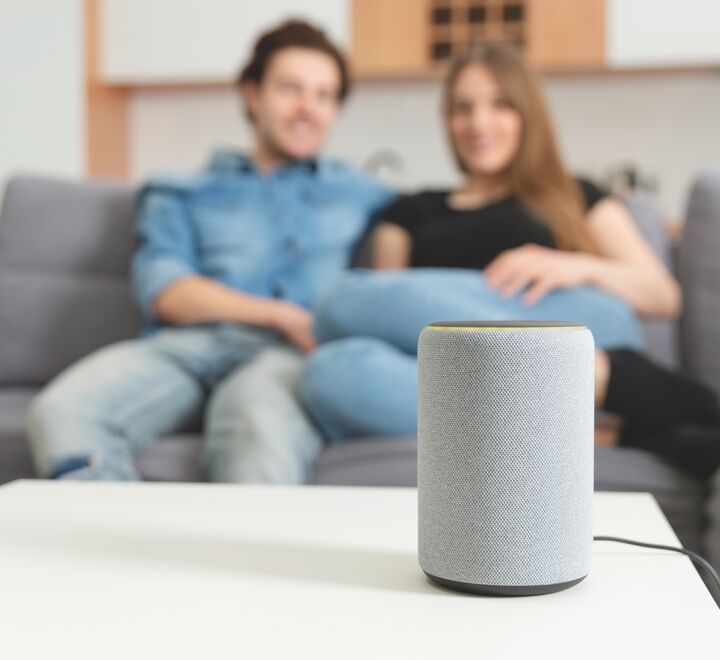 Smart speaker on a table in front of a couble in a sofa