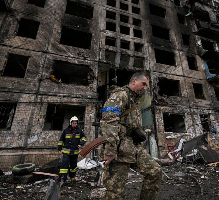 Bilde fra Kyev 14. mars. Brannmann og soldat går foran skadet bygning (foto: AP Photo/Vadim Ghirda).