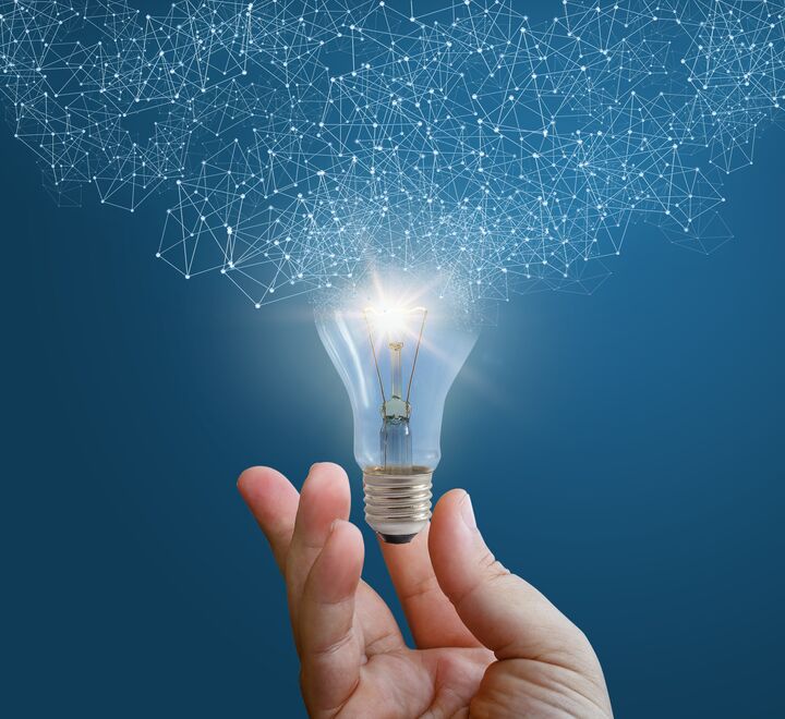 Blue background with a hand holding a light bulb. The light bulb is on and lights up.