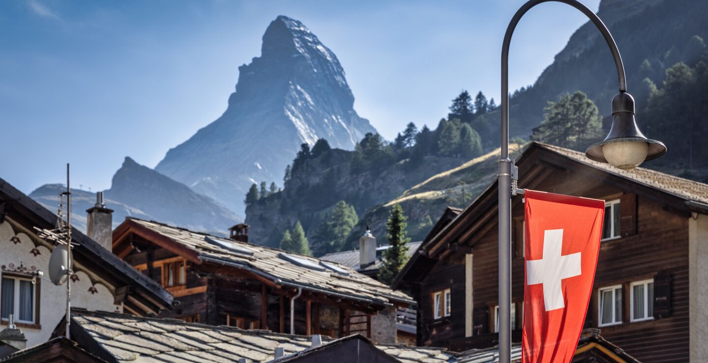 Swiss flag set against a village with Matterhorn in the background.