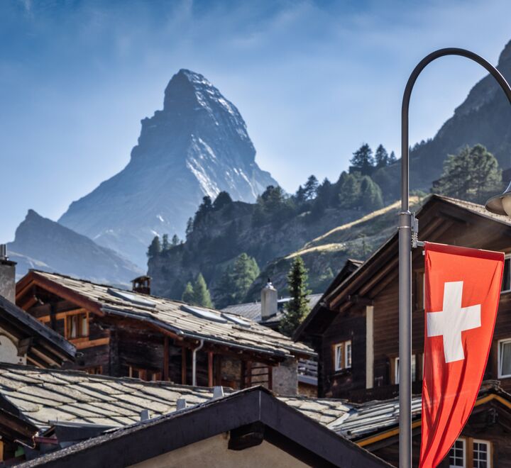 Swiss flag set against a village with Matterhorn in the background.