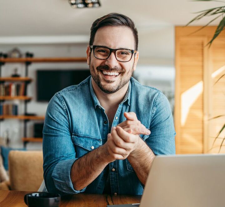 Mann bak PC smiler til kamera