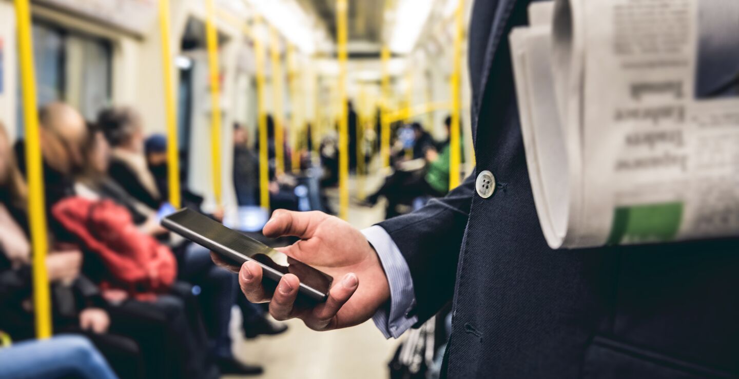 Mann som leser på mobilen på t-banen.