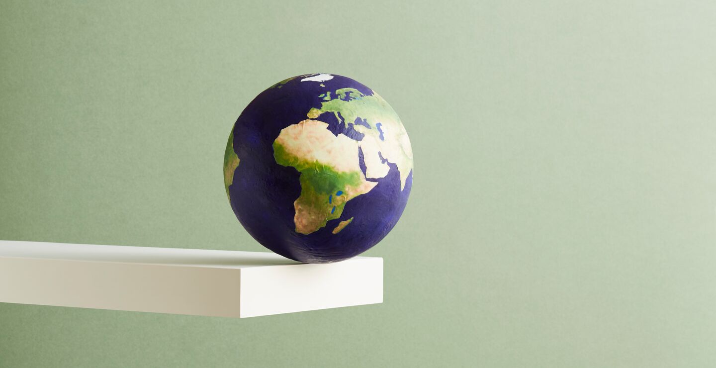 Earth about to fall off a plank set against a green backround