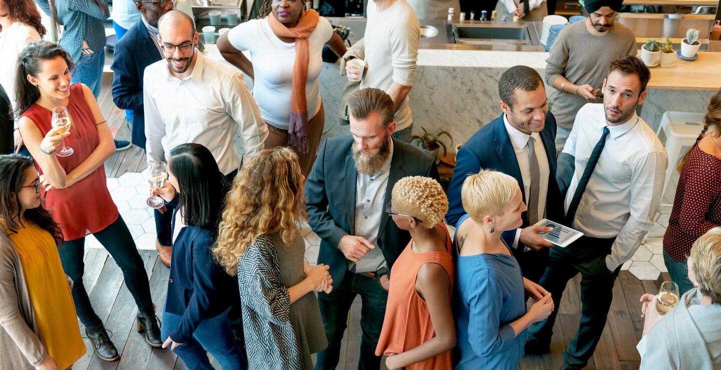 En kvinne strekker ut hånden for å hilse, mens kolleger står i bakgrunnen