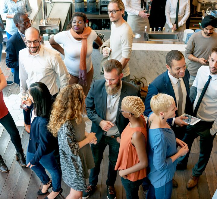 En kvinne strekker ut hånden for å hilse, mens kolleger står i bakgrunnen