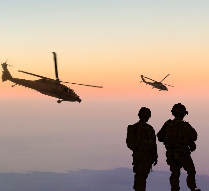 Siluett av helikopter og to mennesker i forgrunnen