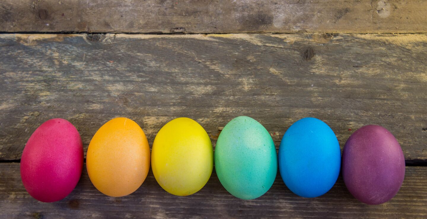 Easter eggs in different colours in front of background made out of wood