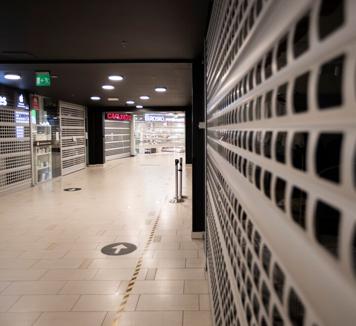 Bilde tatt inne i et tomt kjøpesenter med stengte butikker.