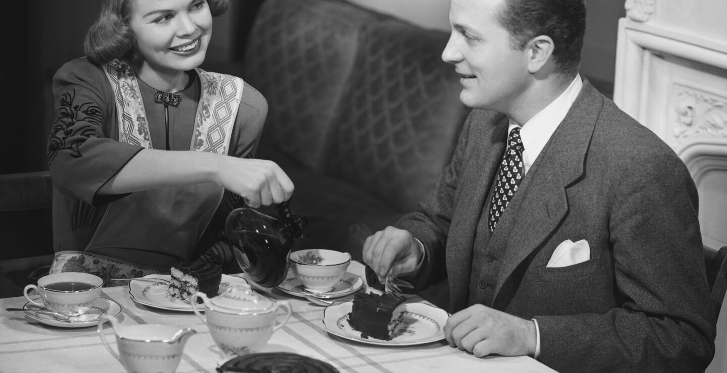 Historisk bilde: En husmor serverer sin mann te  ved spisebordet