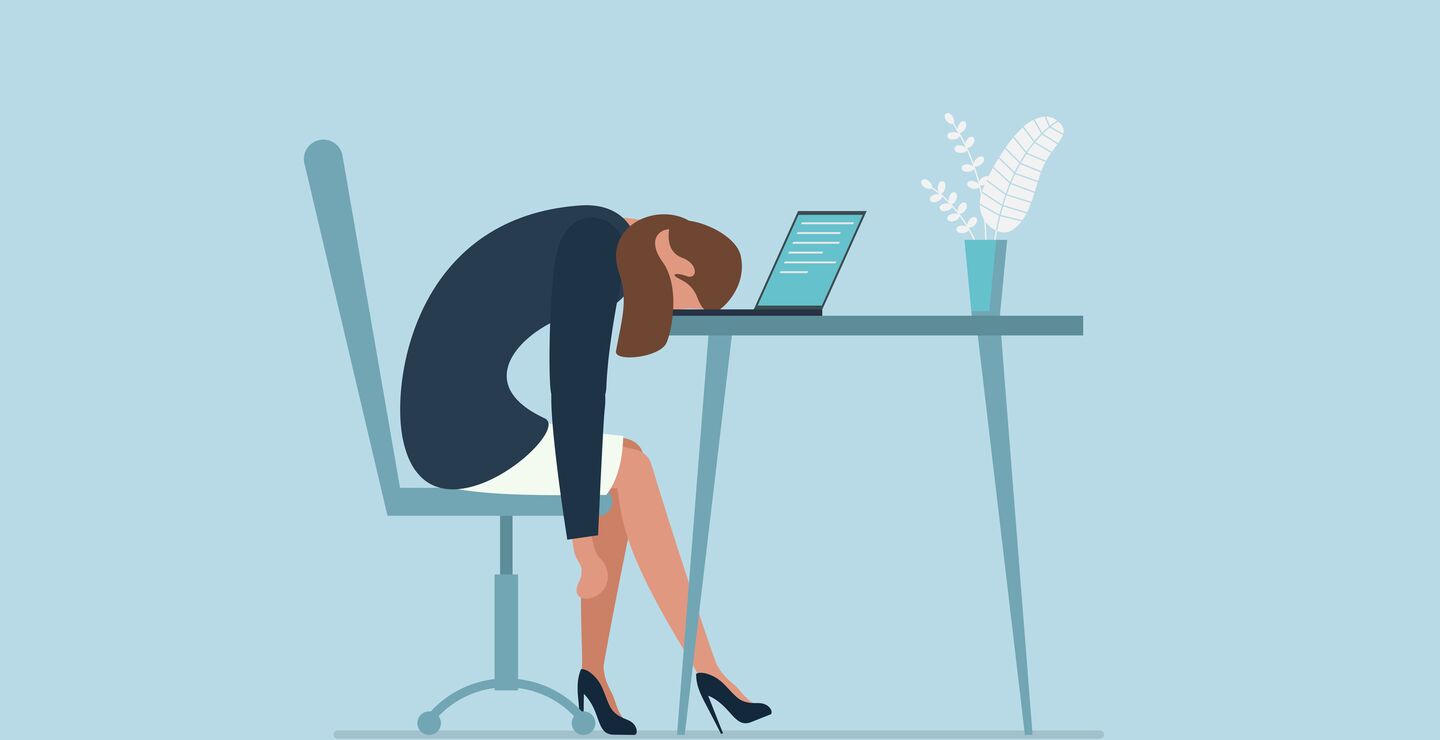 En sliten og stresset kvinne på kontoret ligger med hodet ned i laptopen.
