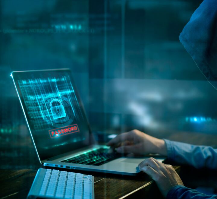 Person med hettegenser over hodet foran en laptop