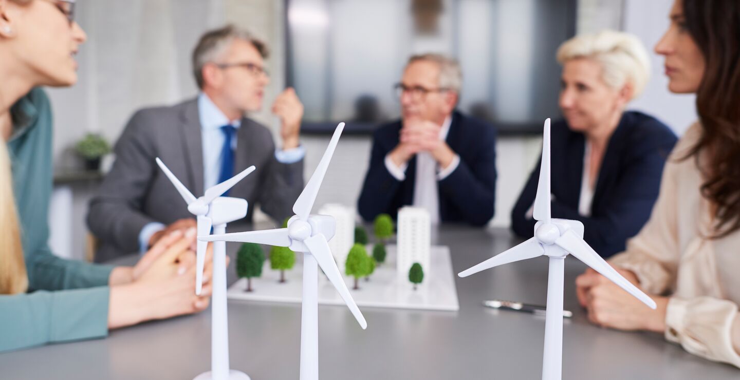 Mennesker i møte med modeller av vindmøller på bordet