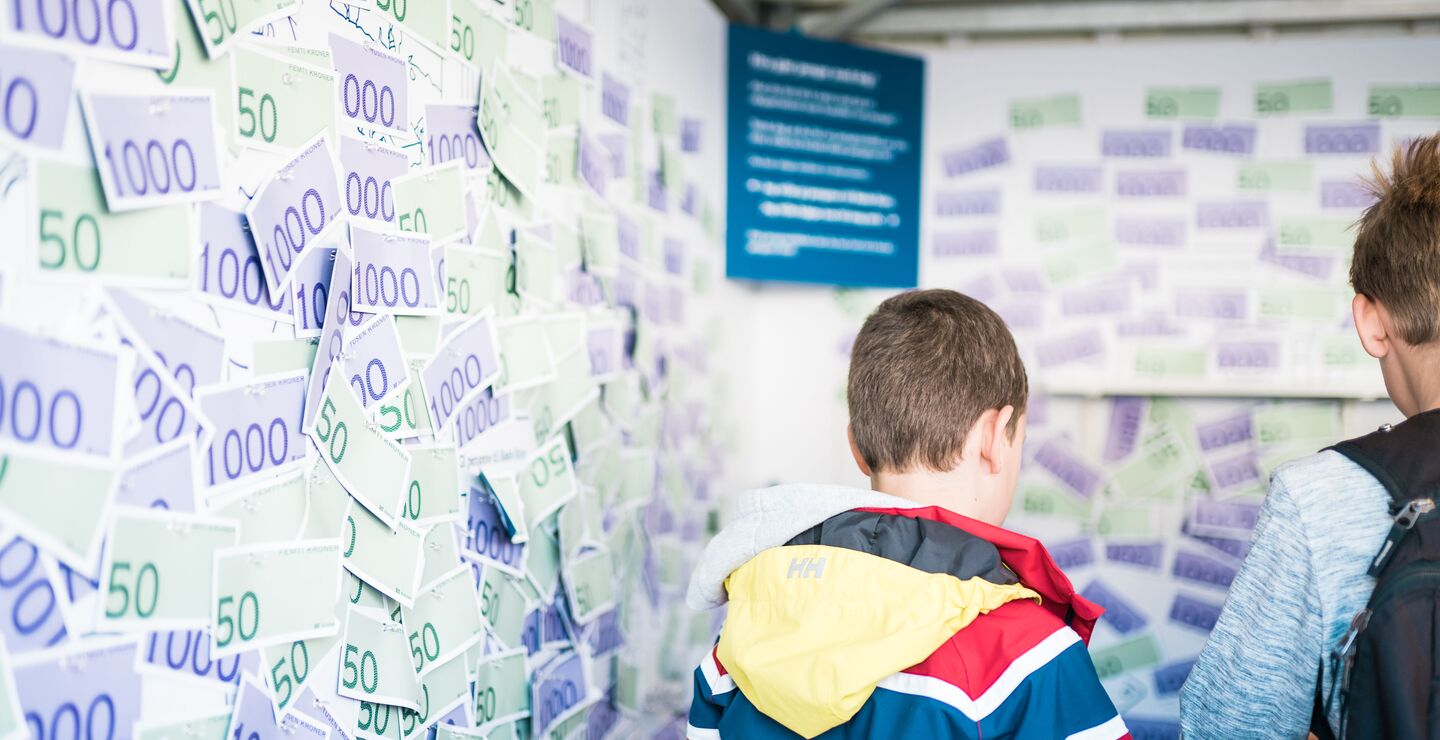 Mann foran en vegg med pengesedler