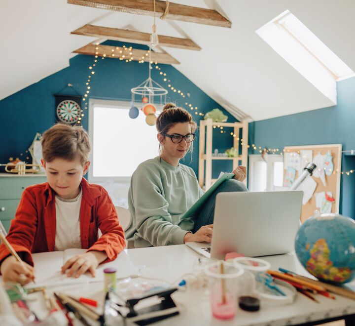 Mange vil fortsette med hjemmekontor etter pandemien. Noen lengter etter å komme tilbake. Her bilde av en mor som jobber hjemmefra samtidig som hun hjelper barnet med lekser. (Foto: Aleksandar Nakic.)
