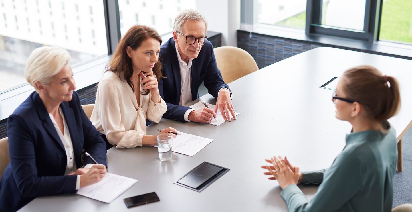 En jobbsøker blir intervjuet av tre personer rundt et bord